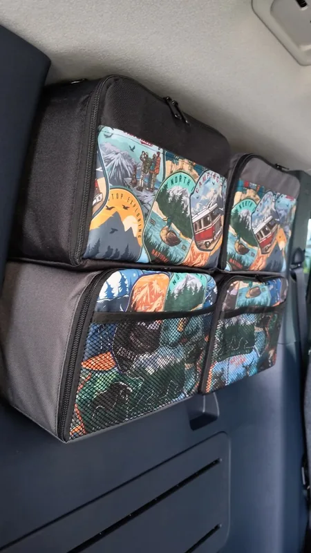 Patterned organizer bags with mesh pockets fitted over a rear side window inside the van.