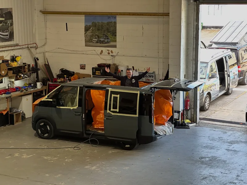 The van in a workshop with its new pop-top roof being fitted